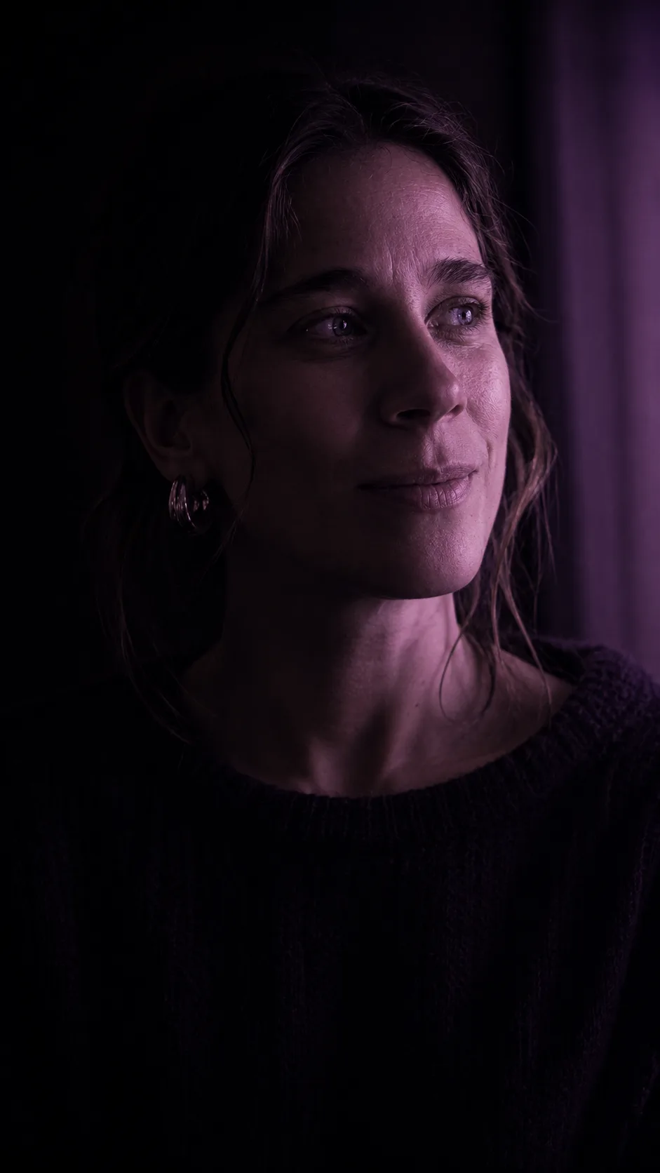 Portrait de R.G., l'autrice, dans une lumière douce et violacée.
